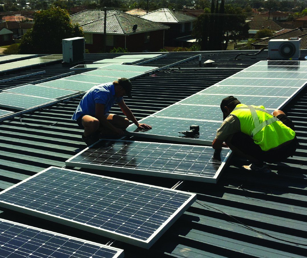 Electricians installing panels on a suburban roof