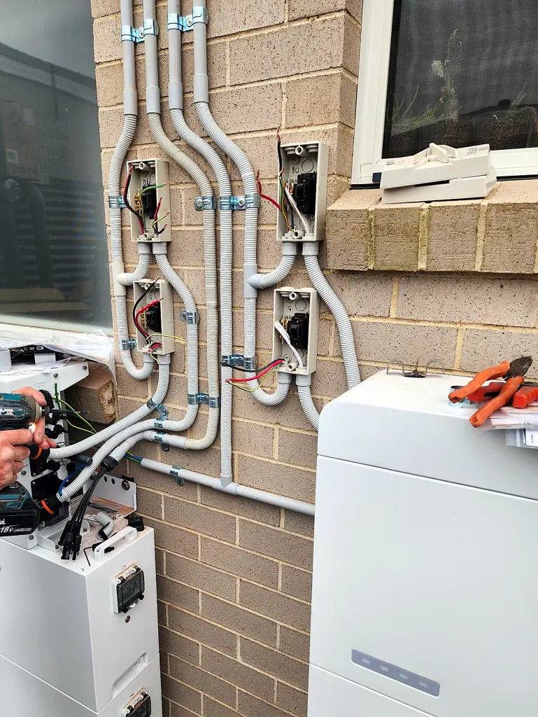 Neat conduit runs and isolator switches beside a home battery