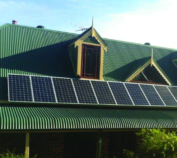 Solar panels on the green Colorbond roof of a Federation-style home