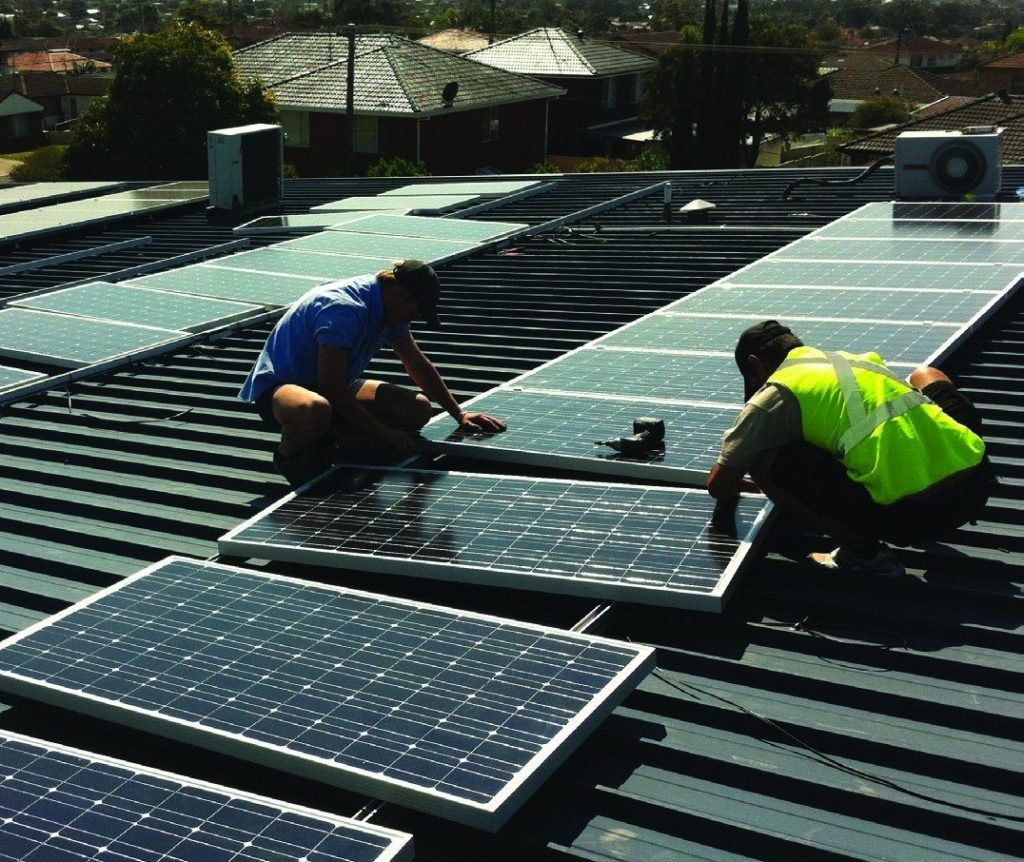 Electricians installing panels on a suburban roof